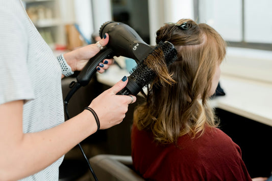 Estilista secando y cepillando el cabello de una clienta en un salón